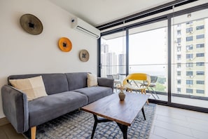 Un salon moderne avec un canapé gris, une table basse en bois et un fauteuil jaune.