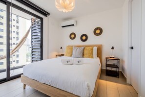 A bedroom with a large bed, a hammock, a wall-mounted air conditioner, and decorative wall art. - w* | Warm 1BR in San Francisco w/ Balcony (Panamá)