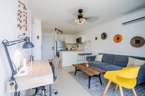 A modern living room with a sofa, a coffee table, and a desk with a lamp. There is a kitchen in the background. - w* | Warm 1BR in San Francisco w/ Balcony (Panamá)