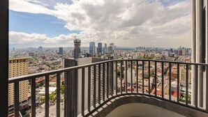 A cityscape view from a balcony with a metal railing, featuring a mix of high-rise buildings and a prominent tower. - w* | Phenomenal 1BR with Amazing view in Cuauhtemoc (Ciudad de México)