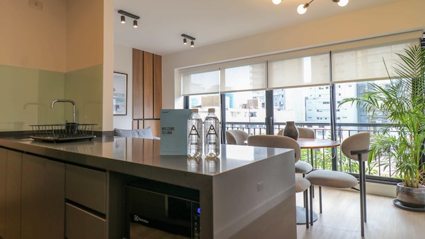 A modern kitchen with a built-in microwave, a bar area with seating, and large windows offering a city view.