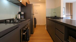 A modern kitchen with a gas stove, coffee maker, and a refrigerator.