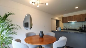 A modern kitchen with wooden cabinets, a central island, and a round dining table with six chairs.