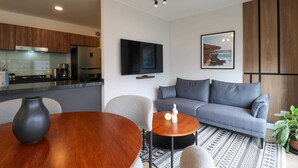 A modern living space with a kitchen, grey sofa, and a dining table with a vase.