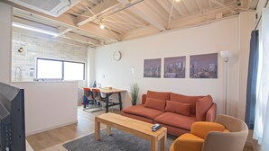 A modern living room with a sofa, a wooden coffee table, and a TV. - Tabi Time Nishinagahori  (Osaka)