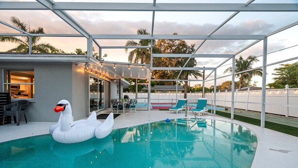 En swimmingpool med en svane-svømmelegetøj, en overdækket patio og udendørs møbler.