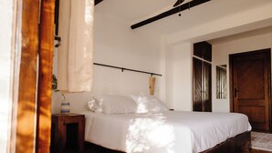 Une chambre à coucher avec un lit, une table de chevet, une porte en bois et une fenêtre.