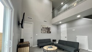 Una sala de estar moderna con sofás grises, un aparador de madera y una mesa de centro redonda.