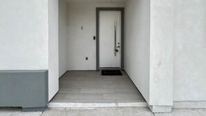 Un couloir étroit aux murs blancs mène à une porte portant le numéro 3.