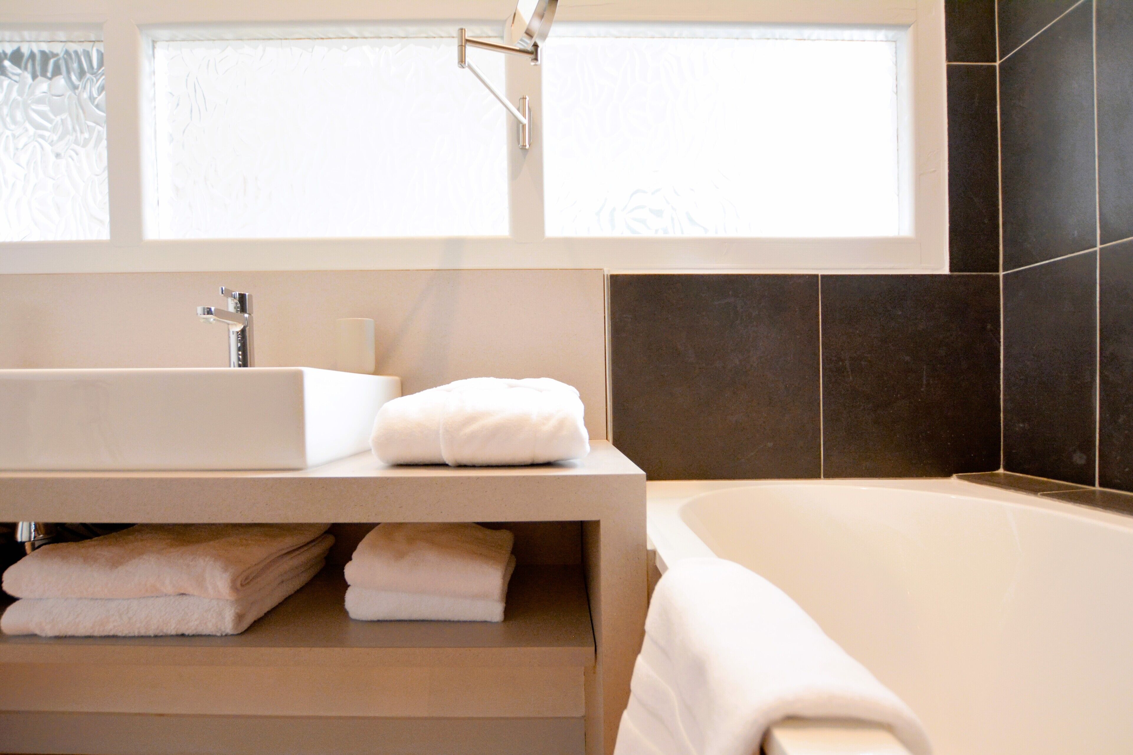 A modern bathroom with a large bathtub, a white sink, and a towel rack.