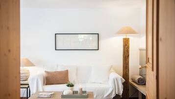 Une pièce chaleureuse avec un canapé blanc, une table basse en bois, une lampe et un tableau encadré au mur.