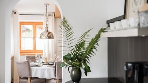 A dining area with a table set for four, a potted plant, and a coffee machine. - Haus Lesch - Stilvolle Appartements mit tollem Bergblick in Kreuth am Tegernsee (Kreuth)