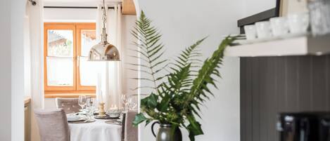 Un comedor con una mesa dispuesta para cuatro personas, una planta en maceta y una cafetera.