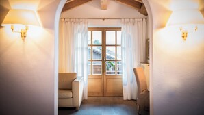 An arched doorway leading to a room with a wooden floor, a beige sofa, and a chair. - Haus Lesch - Stilvolle Appartements mit tollem Bergblick in Kreuth am Tegernsee (Kreuth)
