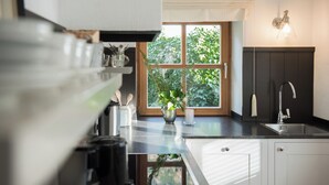 A modern kitchen with a large window, a sink, and a coffee maker. - Haus Lesch - Stilvolle Appartements mit tollem Bergblick in Kreuth am Tegernsee (Kreuth)