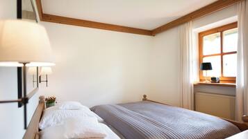 Un dormitorio con una cama, una mesita de noche, una lámpara, una ventana con cortinas y un radiador.