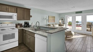 A kitchen with a built-in microwave, stove, and dishwasher, a granite countertop, and a large island with a sink. - Direct ocean view Villa Capriani - just renovated! (North Topsail Beach)