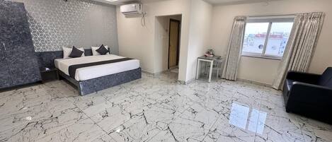 A spacious bedroom with a large bed, marble flooring, ceiling fans, and a window with curtains.