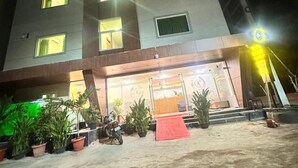 A multi-story building with illuminated windows and a red carpet leading to the entrance.