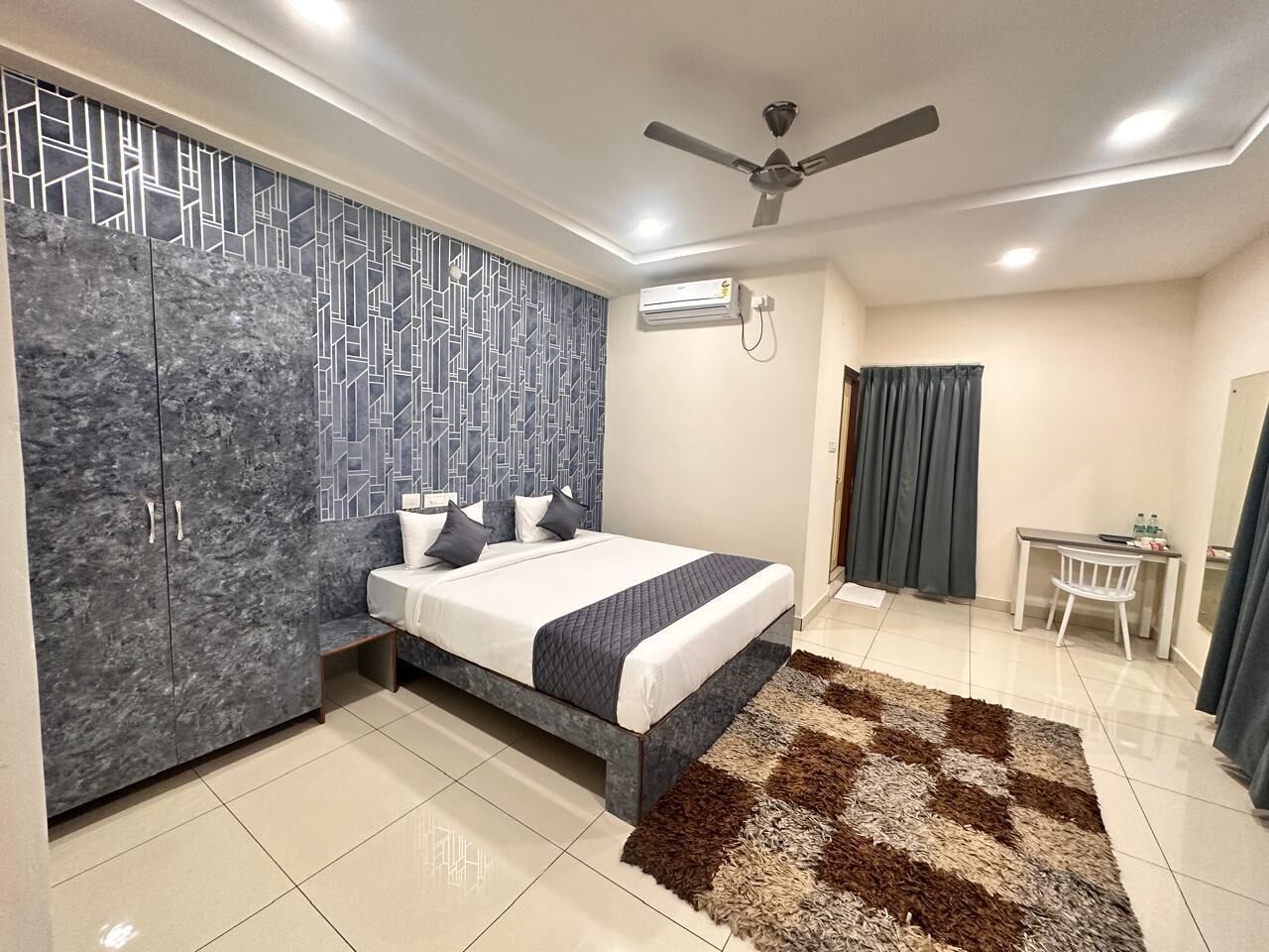 A modern bedroom with a bed, wardrobe, desk, and curtains.