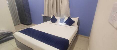 Un dormitorio ordenado con cama, cortinas y una puerta.