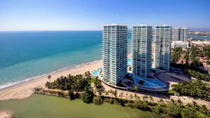 A high-rise hotel with multiple floors, a pool, and a beach view. - Grand Venetian Beachfront Condo (Puerto Vallarta)