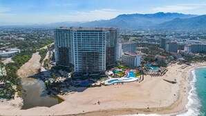 A high-rise hotel with a pool area and beach access. - Grand Venetian Beachfront Condo (Puerto Vallarta)