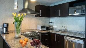 A modern kitchen with dark cabinets, stainless steel appliances, a built-in microwave, and a coffee maker. - Grand Venetian Beachfront Condo (Puerto Vallarta)