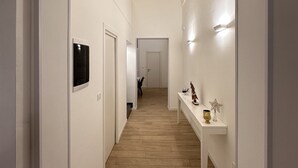 A hallway with white walls, a wooden floor, and a white console table with decorative items.