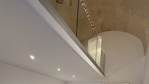 A spacious living area with a grey sofa, a small round table, and a staircase leading to an upper level.