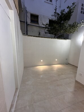 A clean, tiled courtyard with a low wall and a tree.
