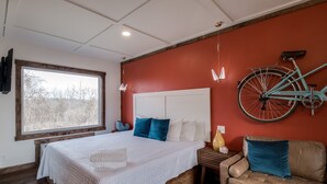 A bedroom with a large bed, a bicycle mounted on the wall, a window, and a wooden floor. - Extended Stay | With Kitchen | Prescott Studio (PRESCOTT)