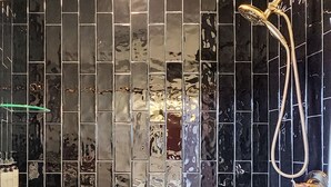 A bathroom with a black tiled shower enclosure and a white bathtub. - Work & Stay | Free Parking | Simple Comfort (Prescott)