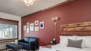 A bedroom with a bed, a chair, a bedside table, a lamp, and framed pictures on the wall. - Work & Stay | Free Parking | Simple Comfort (Prescott)