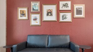 A room with a blue leather sofa, a red textured wall, and several framed pictures. - Work & Stay | Free Parking | Simple Comfort (Prescott)
