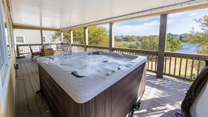 Un jacuzzi en una terraza de madera con vista a un lago y montañas.