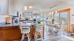 Una cocina moderna con armarios blancos, un refrigerador de acero inoxidable y una isla grande con taburetes de bar.