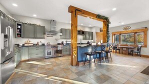 Een moderne keuken met grijze kastjes, roestvrijstalen apparatuur en een houten boog.
