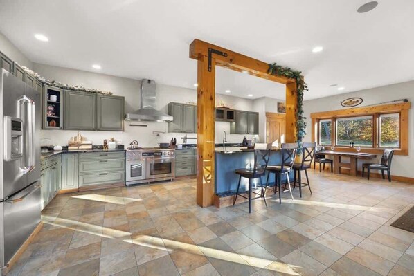 A modern kitchen with grey cabinets, stainless steel appliances, and a wooden archway. - The Lodge at Branch Pond (Ellsworth)