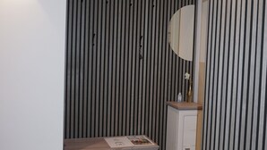 Ein modernes Badezimmer mit einer gestreiften Wand, einem Waschtisch inklusive Spiegel und einem gemusterten Boden.