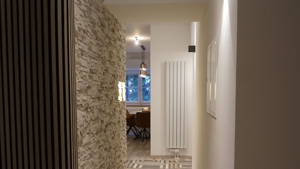Ein Flur mit einem gemusterten Teppich, einer Steinwand und einem Essbereich im Hintergrund.