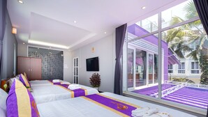 A hotel room with two beds, a TV, and a large window with a view of a pool and palm trees.