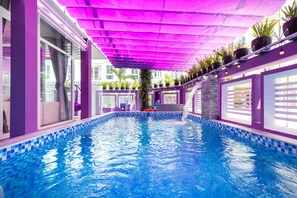 An indoor swimming pool with a tiled edge, surrounded by purple walls and a canopy. - Villas 126-G1 Vung Tau (Ho Chi Minh City)