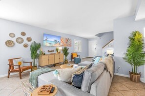Una sala de estar con sofá, sillones, un mueble de madera y decoración mural.
