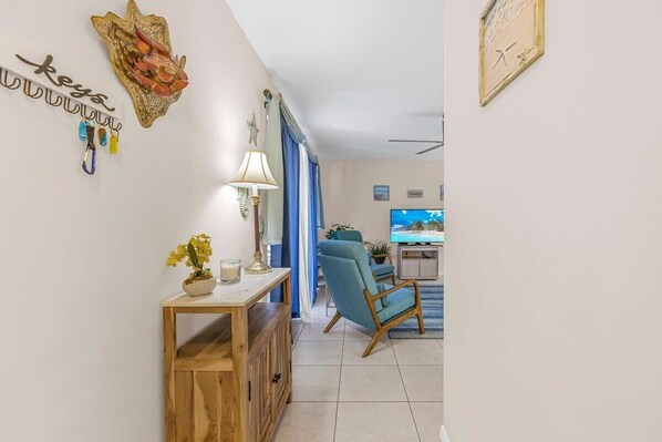 Un salon avec un téléviseur, une console en bois et un fauteuil bleu.