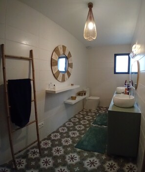 A bathroom with a wooden ladder, a round mirror, a toilet, a sink, and a patterned floor.