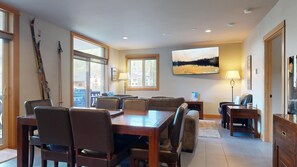 Un comedor con una mesa y sillas de madera, una chimenea y vistas a las montañas.