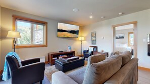 Una sala de estar con sofá, sillones, una mesa de centro, chimenea, televisor y un cuadro.