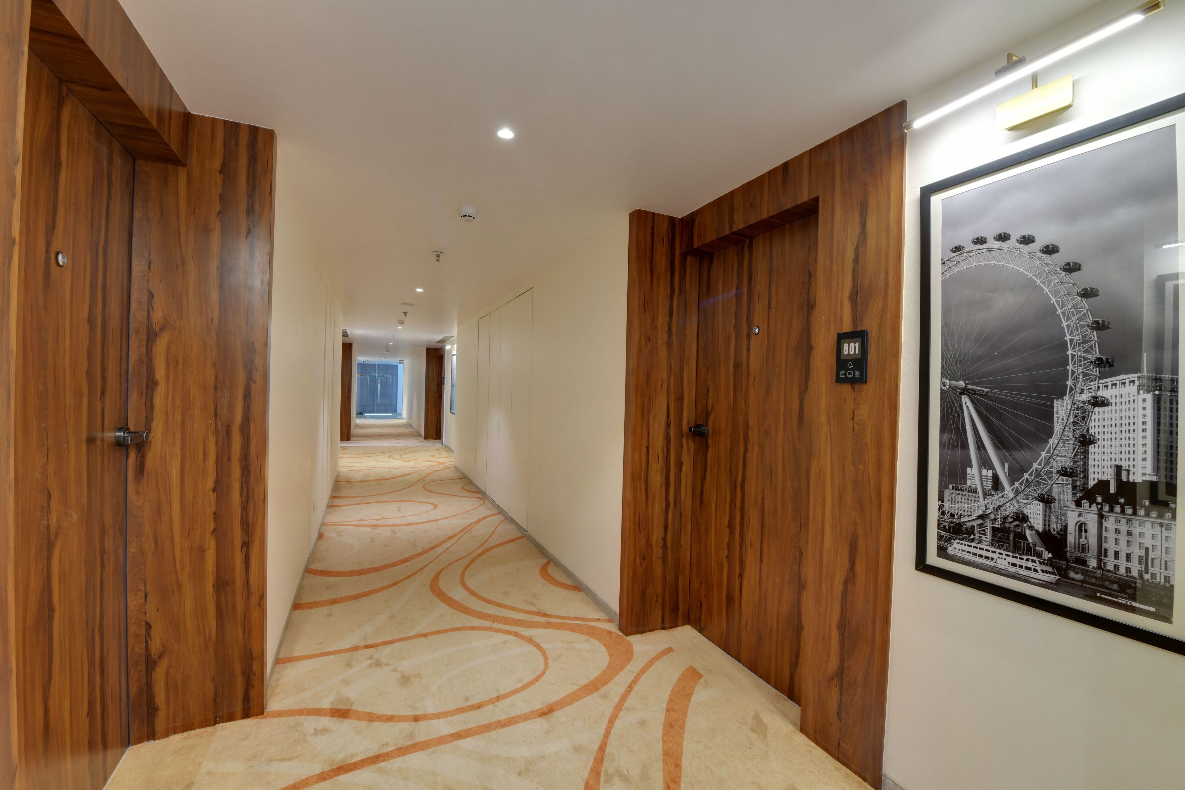 A hallway with wooden paneling and a carpet with orange swirls.
