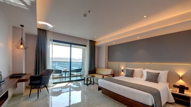 Een moderne hotelkamer met een groot bed, een bureau, een stoel en uitzicht op zee.